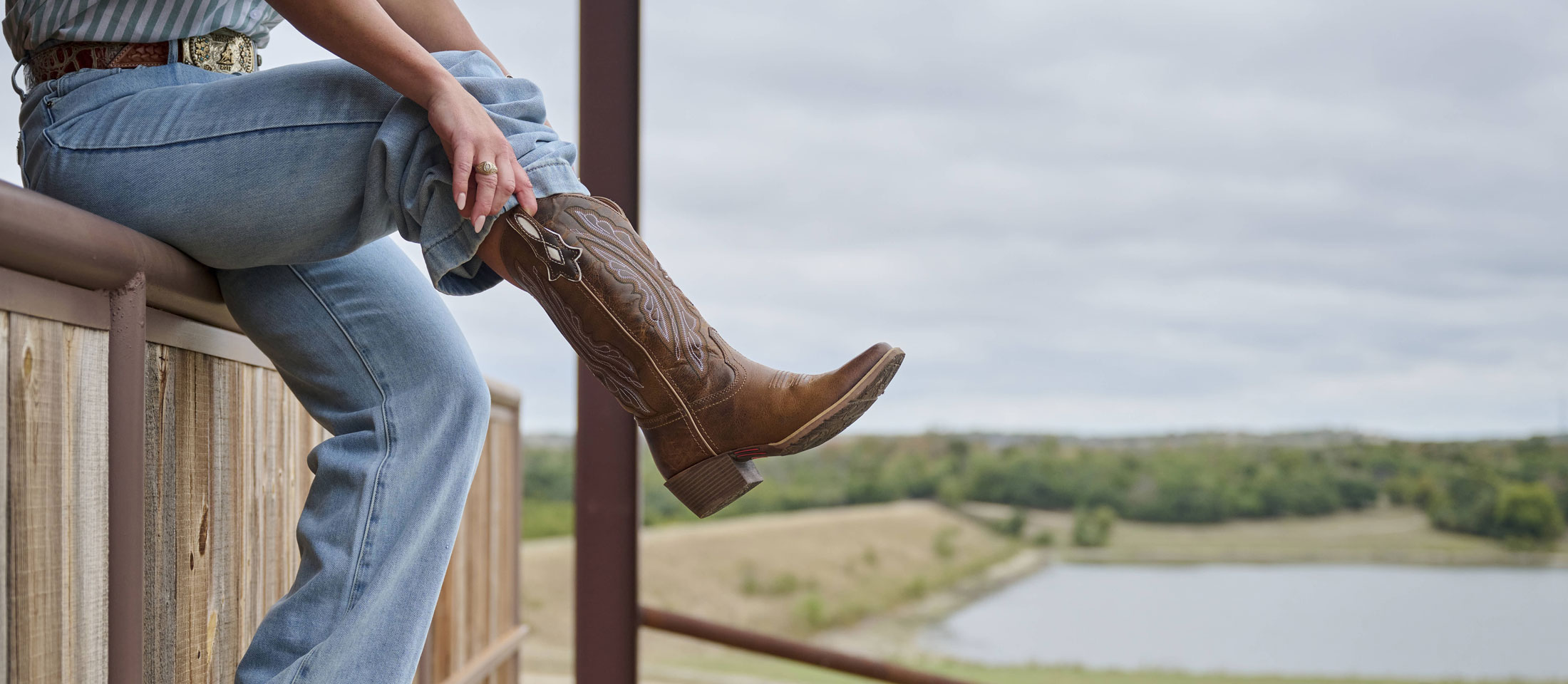 A woman pulling on a pair of cowboy boots.